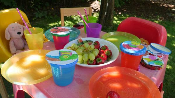Auf dem Tisch stehen Gläser, Teller, Obst und die gebastelte Sommerdeko