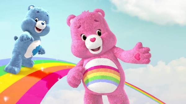 Hurrabärchi (pink) und Schlummerbärchi (blau) sind auf einem bunten Regenbogen.