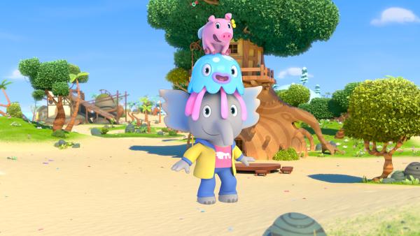 Auf dem Kopf von Mamfie sitzt Takolo. Darüber sitzt Pinkie. Im Hintergrund sind Bäume und Strand zu sehen. 